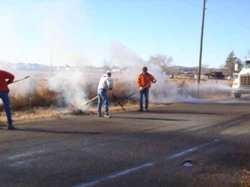 Public workers use large rakes to push away hot ta